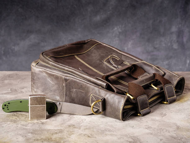 istock Green folding EDC knife and silver lighter near a leather business bag 1468722984