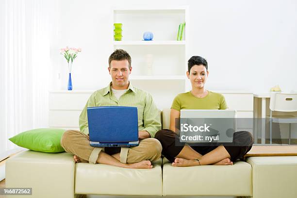 Couple Sitting On The Sofa And Using Laptops Stock Photo - Download Image Now - 20-24 Years, 20-29 Years, 30-34 Years