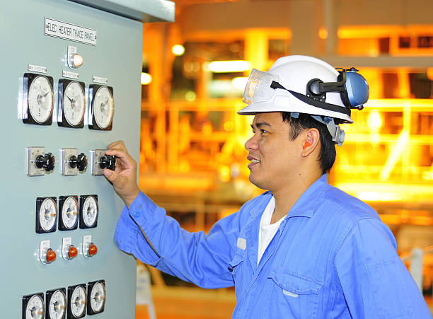 Man with hard hat on turning knob A shipping engineer manages boiler automation panel devices superintendent stock pictures, royalty-free photos & images