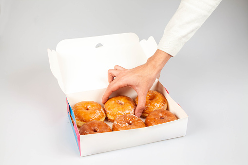 Donut packaging mock up template with hand holding a plain glazed donut.