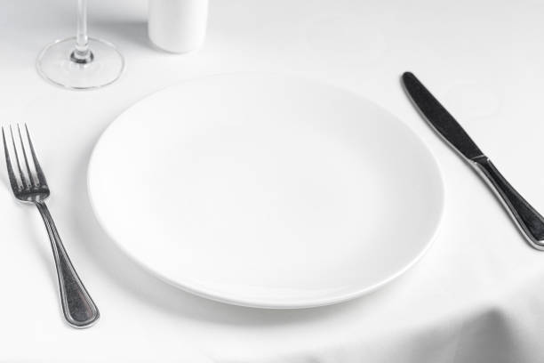 istock Empty white plate with fork and knife on white tablecloth in restaurant. Mock up, template, display. 1468728493