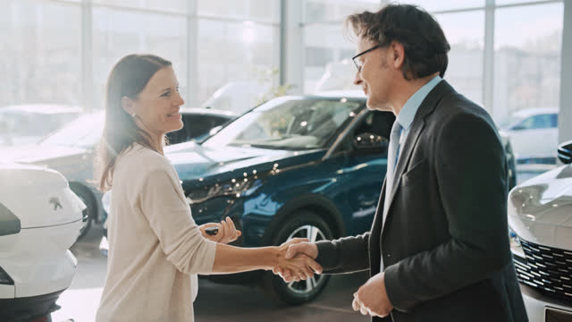 SLO MO Car salesman hands over the keys to a new car to a female customer