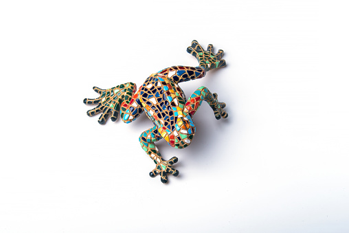 Frog figurine, decorated in the style of Gaudí from small pieces of tiles on white background. Souvenir for tourists. Toy. Barcelona, Catalonia, Spain.