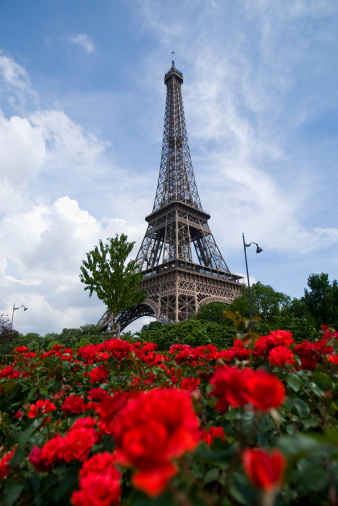 A vertical low angle shot of the Eiffel Tower against a blue cloudy sky in Paris, France