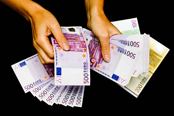 Euro currency in hands on black background. stock photo