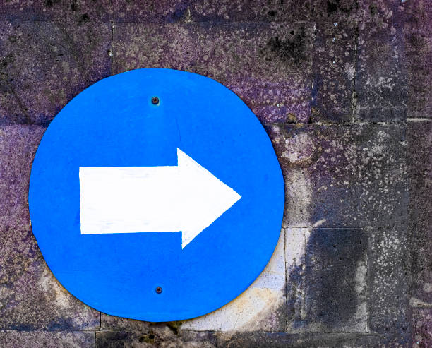 istock Blue circle sign with directional arrow on concrete block wall 1468740827