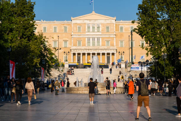 cidadãos de atenas e turistas vagando na praça syntagma à tarde. vista do parlamento helênico e syntagma, sol da tarde - syntagma square - fotografias e filmes do acervo