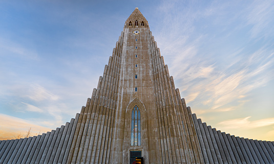 Symmetrical view of the minimalist architecture of Hallgrímskirkja Cathedral based on the basalt formations of Iceland illuminated by the first light of dawn.