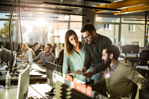 Group Of Computer Programmers Working On Reports At Corporate Office ...