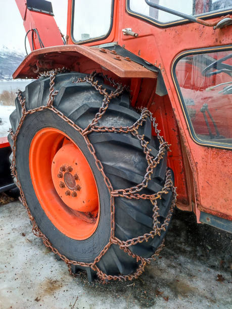 Tractor tire with snow chain for winter service on icy road in winter stock photo
