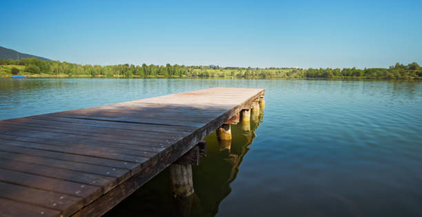 Scenics view of empty deck over blue lake against sky.