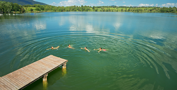 High angle view of four friends swimming in lake water.