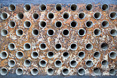 Tube sheet plate of heat exchanger or boiler closeup texture macro industrial background with insoluble hard mineral deposits salts scale welding seams and corrosion. Trypophobia concept.