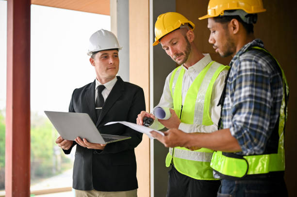 istock Caucasian foreman converses with an Asian construction worker while inspecting the building 1468767845