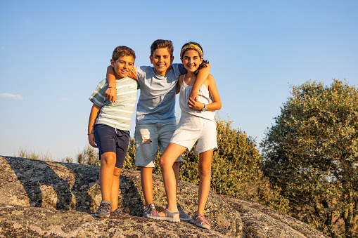 Three kids on a top of a rock on their summer vacation