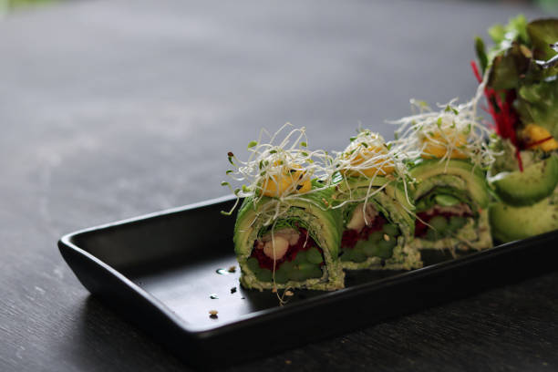 asperges céto végétaliennes avec rouleau de sushi à l’avocat sur assiette noire - sushi styles photos et images de collection