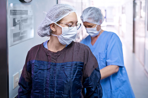 Two female surgeon preparing for surgery, standing in medical clinic and wearing uniforms.