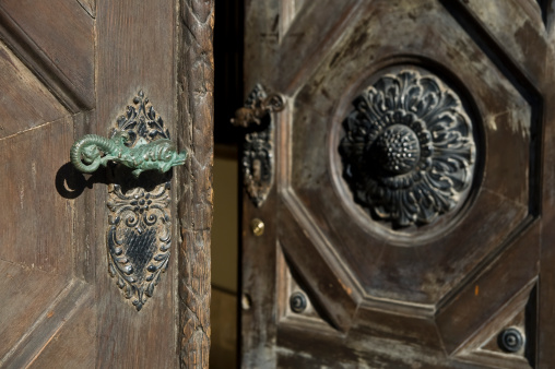 old style entrance door, made of carved massive wood and metal ornamented handle