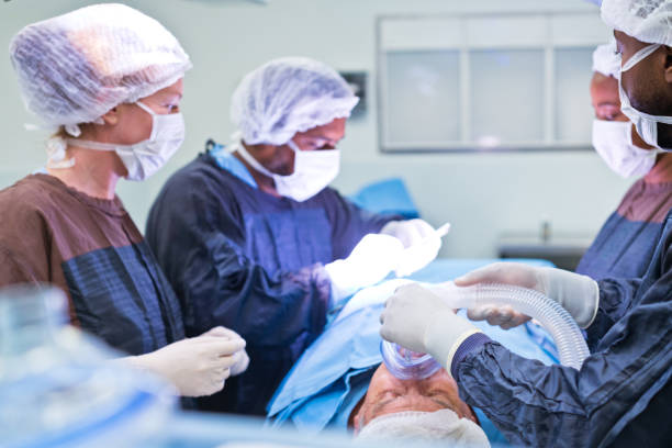 команда хирургов, оперирующих пациента с подсветкой в отделении неотложной помощи больницы - hair net nurse scrubs asian ethnicity стоковые фото и изображения