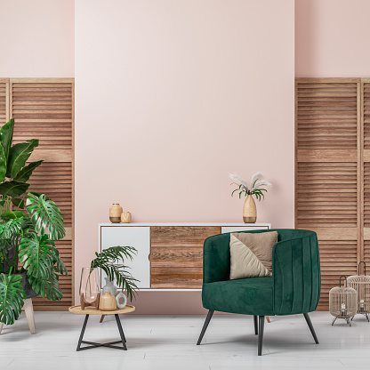 Cozy retro-chic interior with a green velvet armchair and a low white and hardwood cabinet in front of a pastel powder pink plaster wall background with copy space. A low coffee table with ceramic containers, vases on the white hardwood floor, birdcage lamps, and decoration (lush foliage: monstera, banana/palm tree, pillow) with 2 hardwood slat doors on each side. The 50s- 60s decoration, art deco style. A slight vintage effect was added. 3D rendered image.
