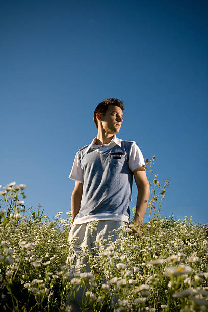 Teenager among flowers Boy among a field of daisies, with a clear blue sky as background and a peaceful atmosphere. beautiful multi colored tranquil scene enjoyment stock pictures, royalty-free photos & images