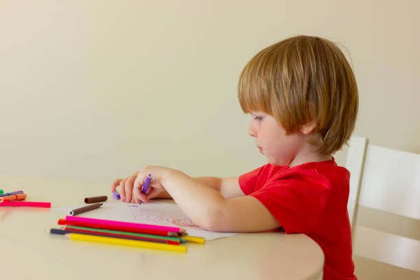 istock painter child boy with colored pencils while sitting attable. childhood, development, education, leisure. 1468787090