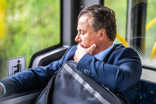 mid adult businessman riding bus looking in window - bus riding public transportation businessman imagens e fotografias de stock