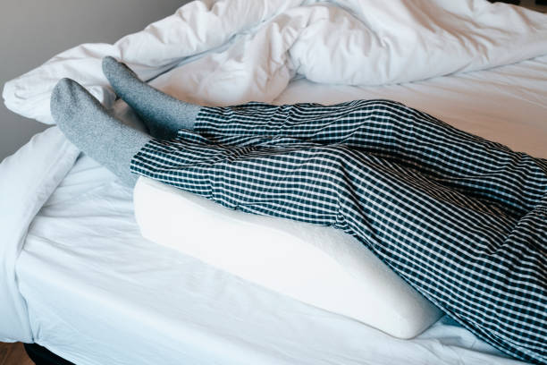 istock leans his legs on a leg elevation pillow, in bed 1468788566