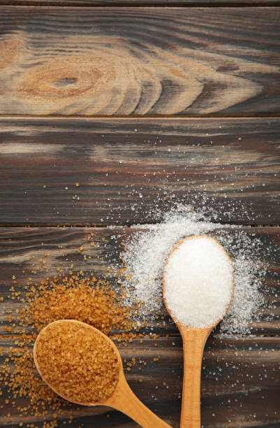 istock White and brown sugar in spoon on brown background. 1468791069
