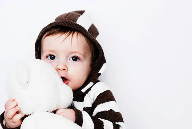 A cute baby boy holding a teddy bear