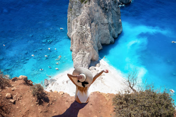 una donna si siede al punto di vista di keri e gode della vista delle famose rocce di mizithres - mountain looking at view beach cliff foto e immagini stock