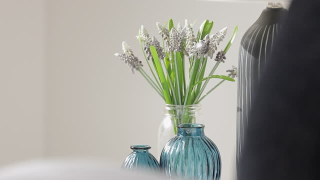 Close up - A vase of beautiful fresh flowers on a nightstand beside a soft, comfortable bed with a warm quilted blanket, perfect for snuggling up on a cold winter day.
