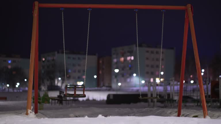 Cinematic empty playground swing, concept of child abduction, cold winter night