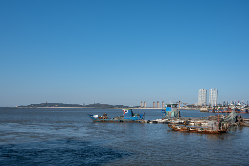 Fishing boats by the sea and tall buildings on the shore