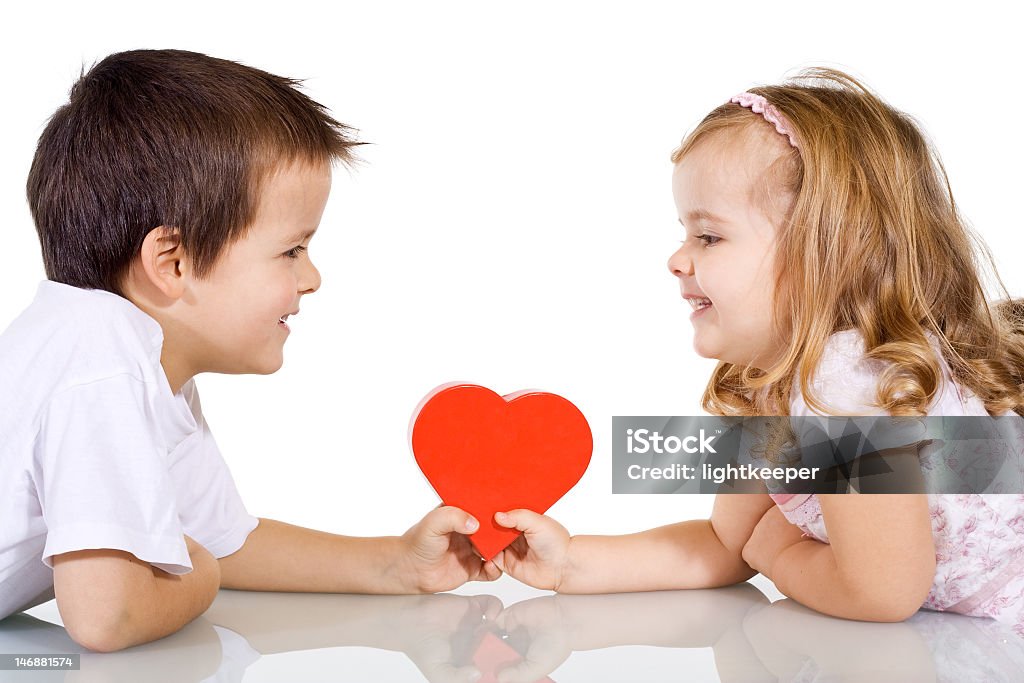 A young boy and girl holding a love heart evenly on a table Two happy kids with valentines heart or birthday gift - isolated Birthday Stock Photo