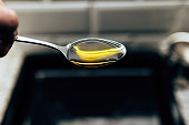 spoon with olive oil in kitchen with white brick wall