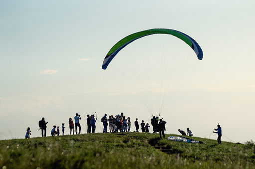 A paraglider takes off from the top of a mountain.