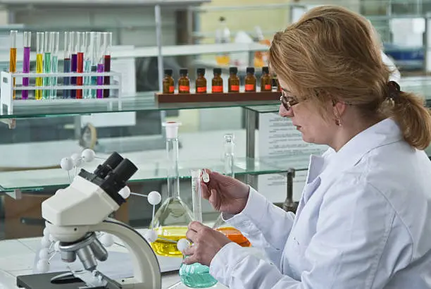 Female researcher opening a glass recipient in the chemistry laboratory.