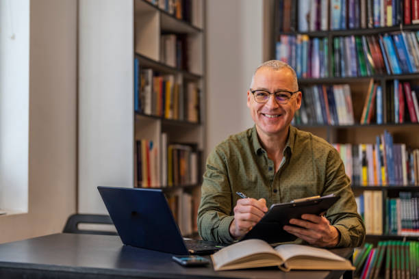 istock Mature man studying in modern library and looking at camera. 1468830556