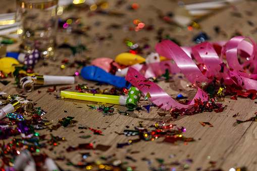 Close up shot of aftermath of a great celebratory party. Colorful confetti, ribbons and party horns.