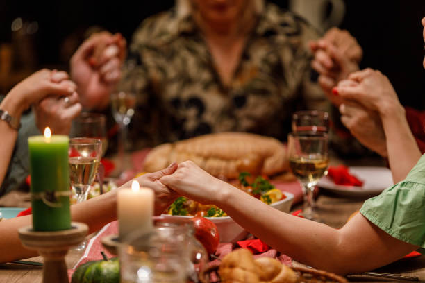 istock Friends holding hands and saying a prayer during a dinner party 1468832303