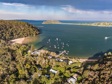 Drone view of Palm Beach and Barrenjoey Head Lighthouse, an affluent beachside suburb in the Northern Beaches region of Sydney, New South Wales, Australia. Seen from Great Mackerel Beach (foreground).