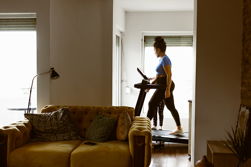 Mother trying to use treadmill at home with her daughter around