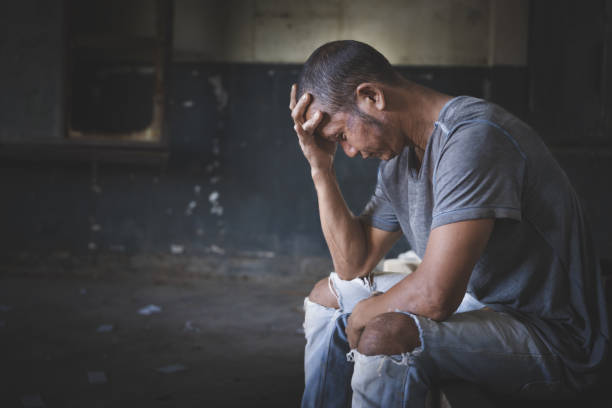 dependência de drogas e conceito de sintomas de abstinência. homem deprimido e sem esperança sentado sozinho depois de usar drogas e beber álcool em casa abandonada. dia internacional contra o abuso de drogas. - narcotic drug abuse cocaine heroin - fotografias e filmes do acervo