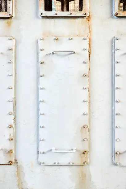 Photo of Three metal hatches plates on compressor for revision close-up with oil stains painted with gray paint bolted with studs and nuts background with copyspace.