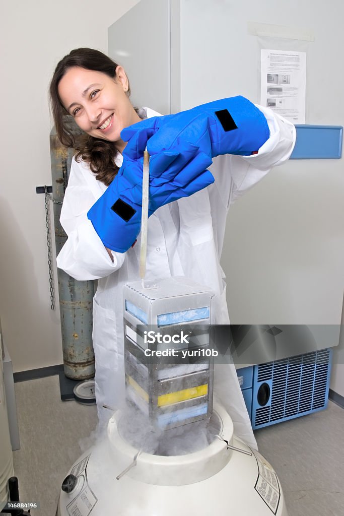 Female scientist freezing tissue culture in liquid nitrogen Scientist freezing tissue culture in liquid nitrogen Cryobiology Stock Photo