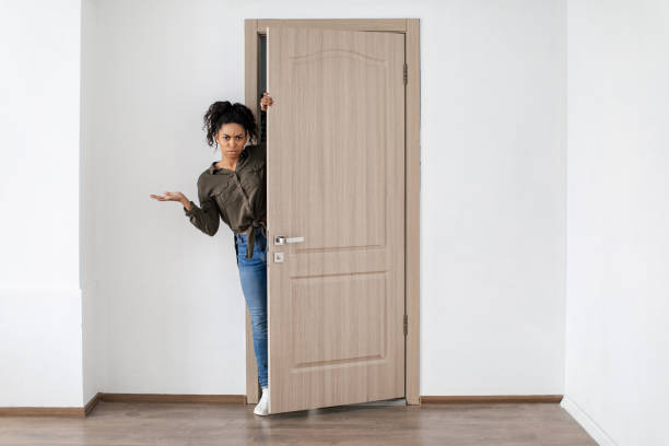 istock Discontented Black Lady Opening Door Looking At Camera At Home 1468842880