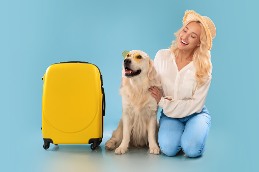 Happy woman posing with dog in sunglasses going on vacation