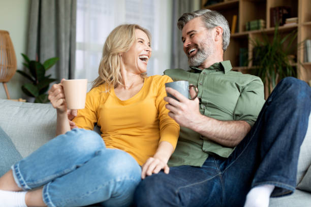 istock Joyful Middle Aged Spouses Relaxing On Couch With Coffee And Chatting 1468842953