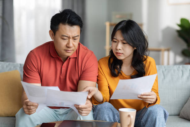 istock Upset asian couple checking bills, home interior 1468844249